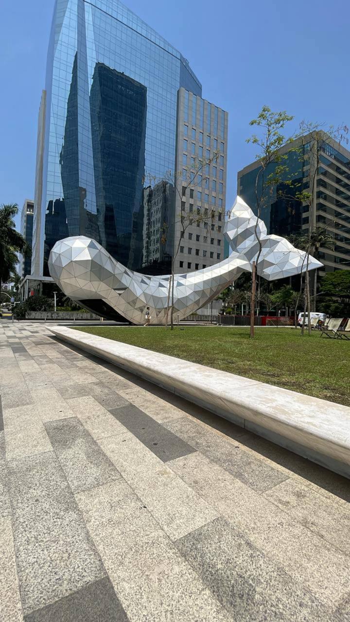 Escultura em branco contra prédios altos em São Paulo, com gramado verde